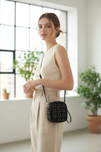 Small black and white checkered pouch with a strap on a light background