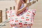 Person holding a tote bag with cherry pattern on a light background
