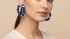 Blue beaded hoop earrings on a white background