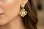 Gold floral earrings with clear gemstones on a white background
