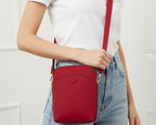Red crossbody bag with gold accents on a white background