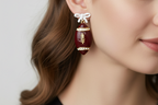 Football-shaped earrings with rhinestone details on a white background