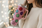 Pink tumbler with smiley face patterns on a white background