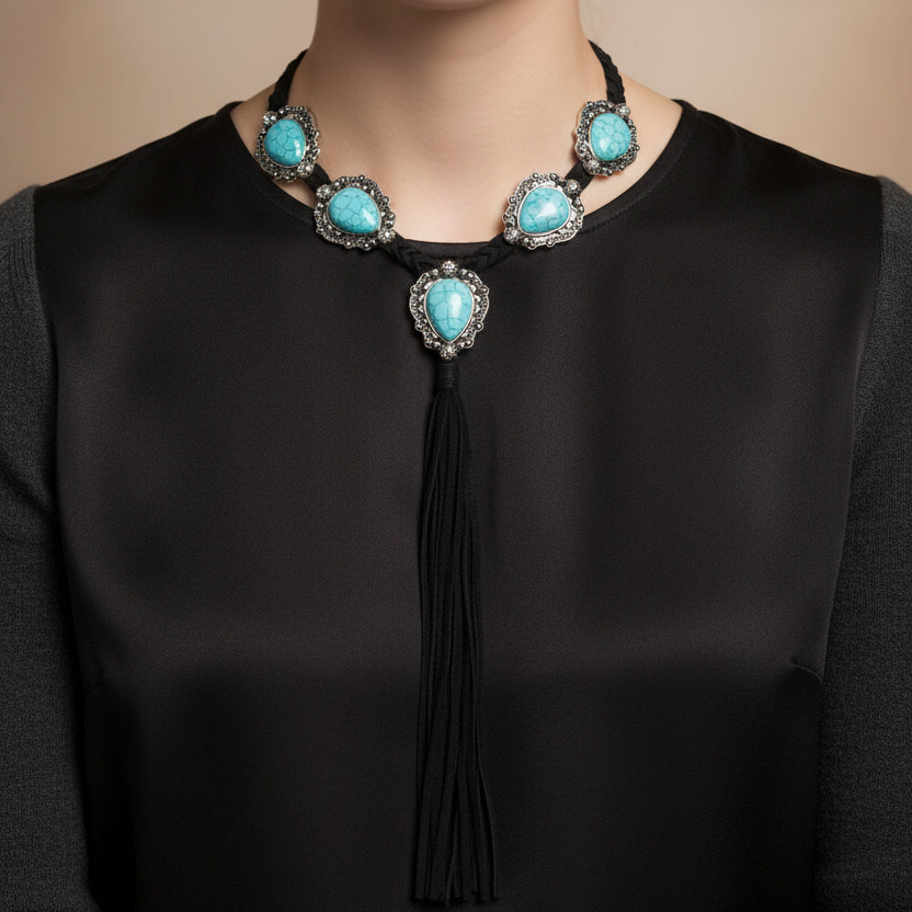 Necklace with turquoise stones and black tassel on a mannequin against a white background