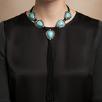 Necklace with turquoise stones and black tassel on a mannequin against a white background