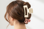 Set of four hair clips in beige, pink, and floral design on a light surface.