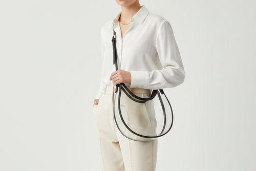 Clear handbag with black handle and trim on a light gray background