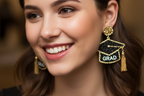 Graduation cap earrings with 'GRAD' text and tassels on a white background