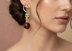 Pair of gold hoop earrings with turquoise and brown beads on a white background