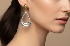 Pair of teardrop-shaped earrings in gold and silver on a white background