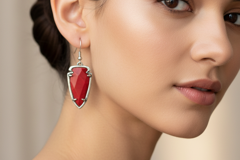 Red arrowhead-shaped earrings with silver frames on a white background
