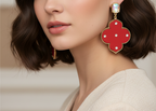 Red earrings with gold accents and clear stones on a white background