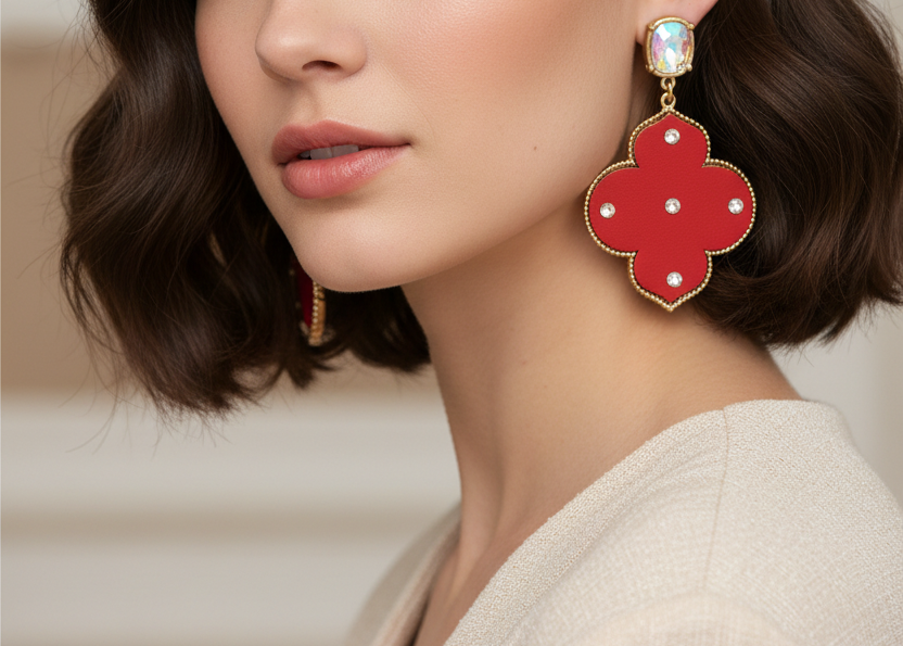 Red earrings with gold accents and clear stones on a white background