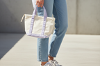 Beige tote bag with purple handles on a beige background